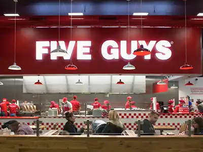 The interior of a Five Guys restaurant with surveillance cameras in the corners of the ceiling.